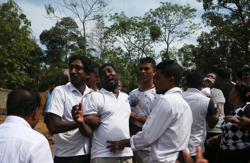 People react during a mass burial in Negombo. Reuters