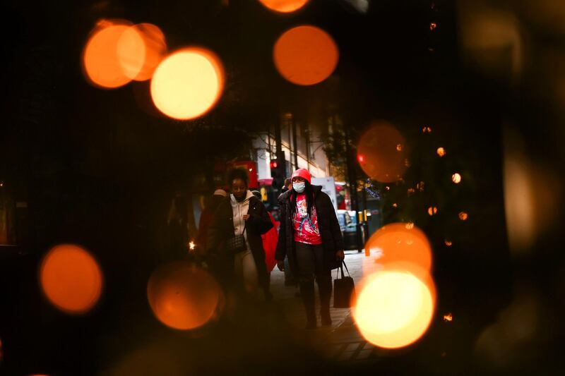 Pedestrians illuminated by Christmas lights walk through Oxford Street. Reuters