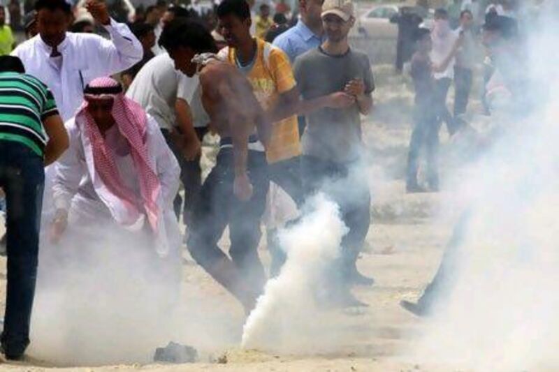 Anti-government protesters bury tear gas canisters fired by riot police Sunday, AP Photo/Hasan Jamali
