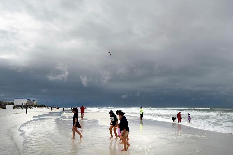 Beachgoers walk on Okaloosa Island in Fort Walton Beach, Fla., Monday, May 28, 2018, as Subtropical Storm Alberto approaches the Gulf Coast. The storm's gusty rain and brisk winds roiled the seas near the U.S. Gulf Coast on Monday, keeping white sandy beaches emptied of their usual Memorial Day crowds. (Nick Tomecek/Northwest Florida Daily News via AP)