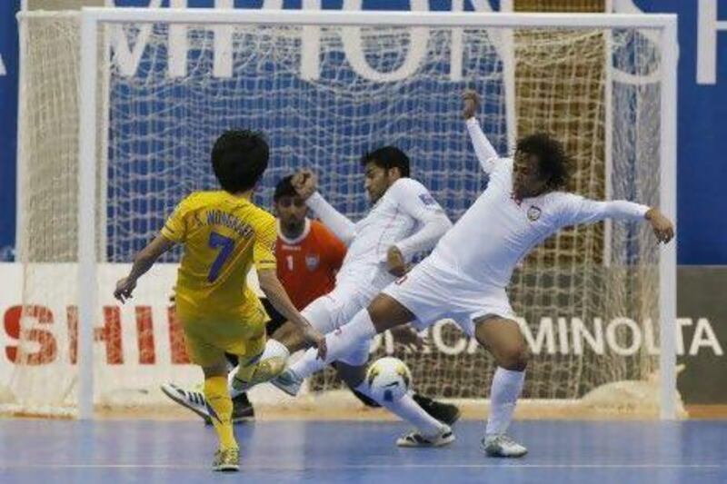 Thailand's Wongkaeo Kritsada shoots on goal as UAE defenders try to block his shot. Thailand defeated the UAE 4-2 to advance to the knock-out stages of the AFC Futsal Championship in Dubai.