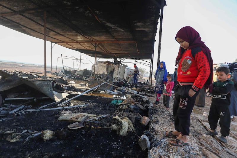 Displaced Syrian youths stand next to their ravaged tent, after a heating device caused a fire at a camp in the rebel-held town of Tal Karamah at the border with Turkey, in the northern countryside of Idlib.  AFP