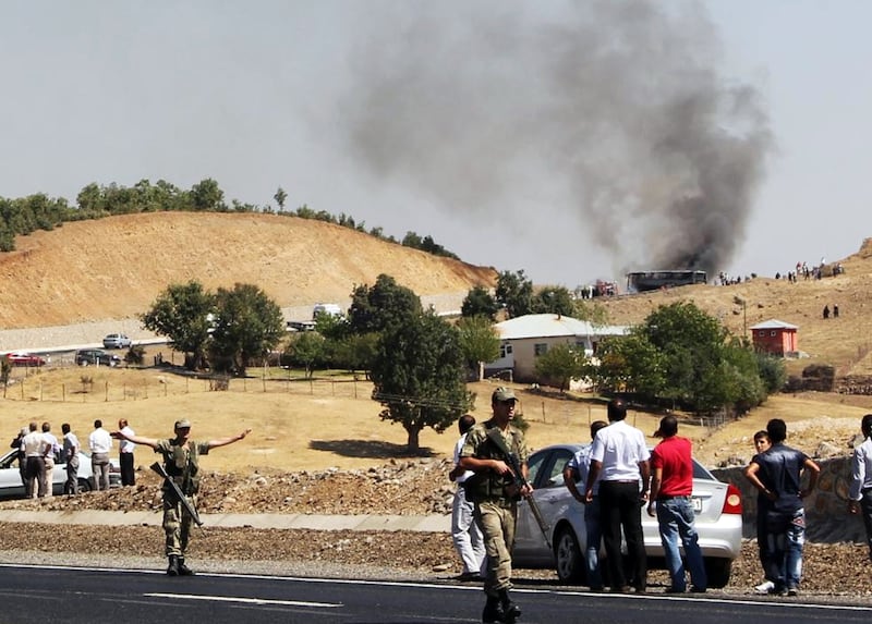 Turkish soldiers stand guard as smokes rises from a bus that was attacked by members of the PKK on September 18, 2012, in Bingol. AFP