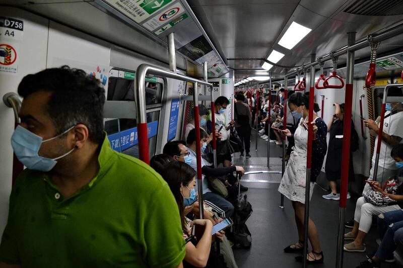 Commuters wear face masks as they travel on a MTR underground metro train in Hong Kong on July 29, 2020, after new social distancing measures came into effect which include everyone having to wear a mask, to combat a new wave of coronavirus infections. / AFP / Anthony WALLACE
