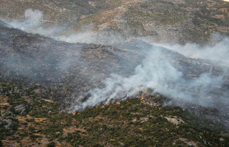 A handout picture released by the official Syrian Arab News Agency (SANA) shows smoke billows from fire in al-Hayluna village, in the western countryside of Syria's Hama governorate.  AFP