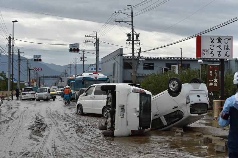 Overturned vehicles sit on the side of a muddy road in Nagano. AFP