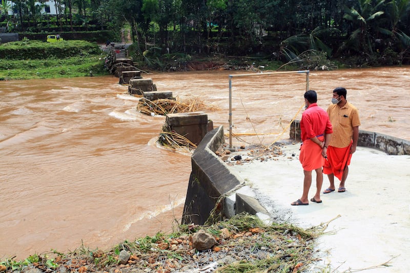 Men stand near the flooded river in Manimala. EPA