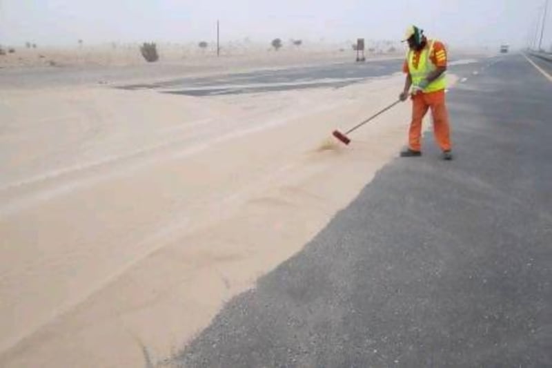 A worker clears sand from the Jabel Ali - Lahbab road after the weekends sandstorms.