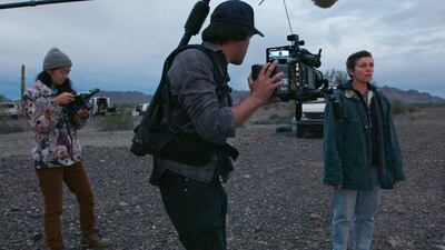 This image released by Searchlight Pictures shows writer-director ChloÃ© Zhao, from left, director of photography Joshua James Richards and actress Frances McDormand on the set of "Nomadland."  Zhao has made cinema of rugged authenticity, relying frequently on non-professional actors and moments of serendipity while filming. She is nominated for a Golden Globe for best director. (Searchlight Pictures via AP)