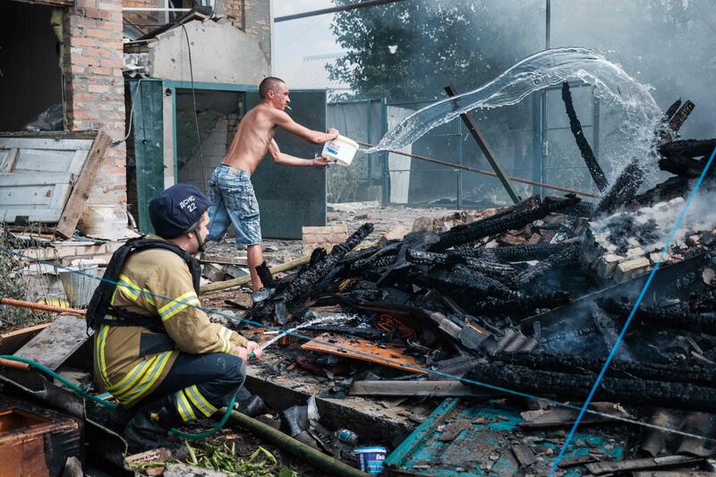 A resident helps a firefighter put out a fire after an air strike in the town of Bakhmut, in the breakaway enclave of Donetsk. AFP