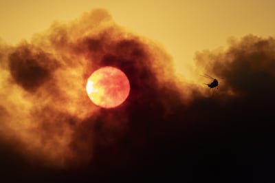 A firefighting helicopter is seen as smoke from the Alisal Fire shrouds the sun near Goleta, California. AFP