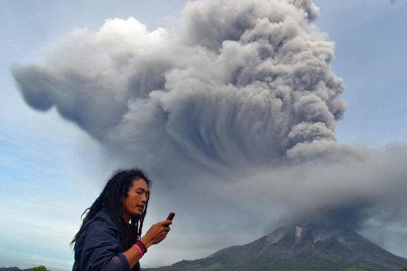 A man uses his mobile phone as Mount Sinabung continues to erupt, with hot smoke spewing from the volcano, in the Karo district on the north of Indonesia’s Sumatra island. Sutanta Aditya / AFP Photo
