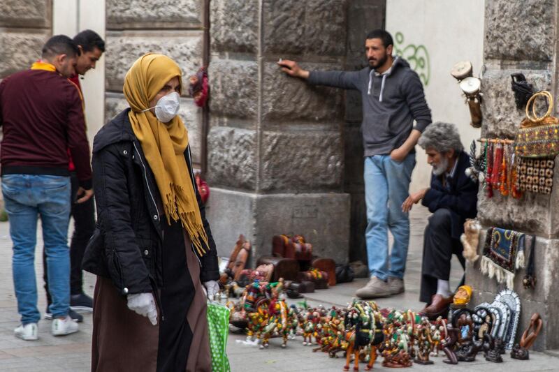 A woman wearing a mask walks past street vendors in Tunis. AP Photo