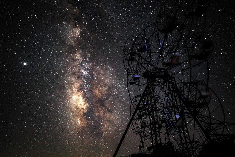 This long-exposure picture shows a view of the Milky Way galaxy rising in the sky behind a children's ride above an abandoned amusement park near Al Nayrab, a village ravaged by pro-government forces bombardment, in Syria's northwestern Idlib province. AFP