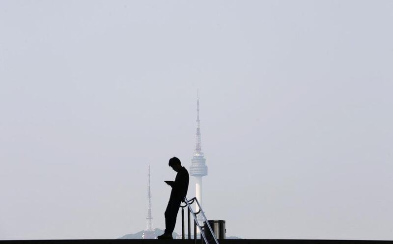 A man using his mobile phone is silhouetted against the backdrop of N Seoul Tower, commonly known as Namsan Tower, in Seoul. Kim Hong-Ji / Reuters