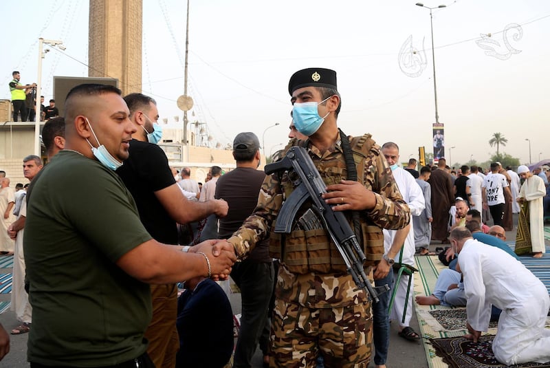 A security guard greets worshippers after prayers on the first day of Eid Al Fitr holiday outside Abu Hanifa mosque in Baghdad, Iraq. AP Photo