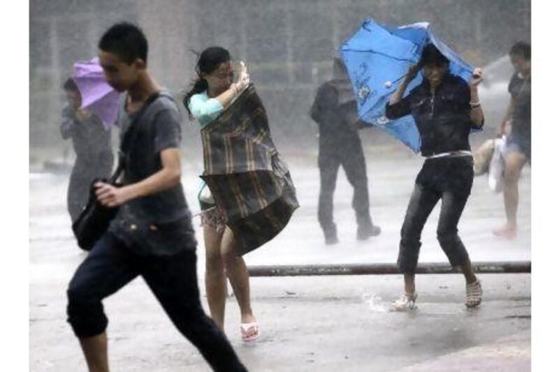 People brave strong winds and rain on a street as a typhoon hit Haikou in south China's Hainan province yesterday. AP Photo