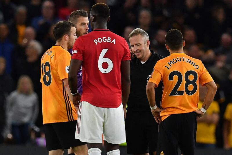 Players react as they wait for English referee Jonathan Moss to give the outcome of the VAR decision for Wolverhampton Wanderers' equaliser scored by Ruben Neves. AFP