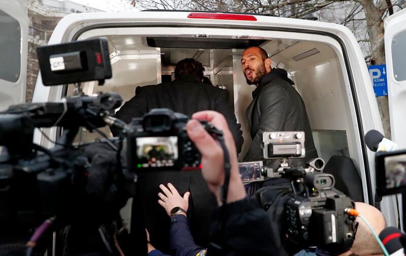 Social media influencer Andrew Tate shouts at the media from the back of a police van in Bucharest. Romanian police say Tate, his brother and their associates coerced victims into pornographic acts. EPA