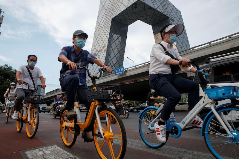 People ride shared bicycles past the CCTV headquarters in the Central Business District in Beijing, China. Reuters