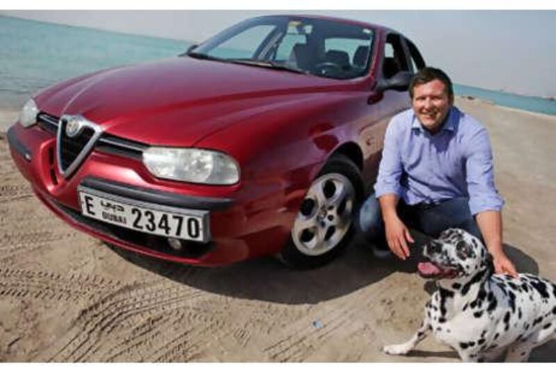 Nathan Wilson and Audrey with his Alfa Romeo. One of them loves hanging their head out of the window while the car is in motion.