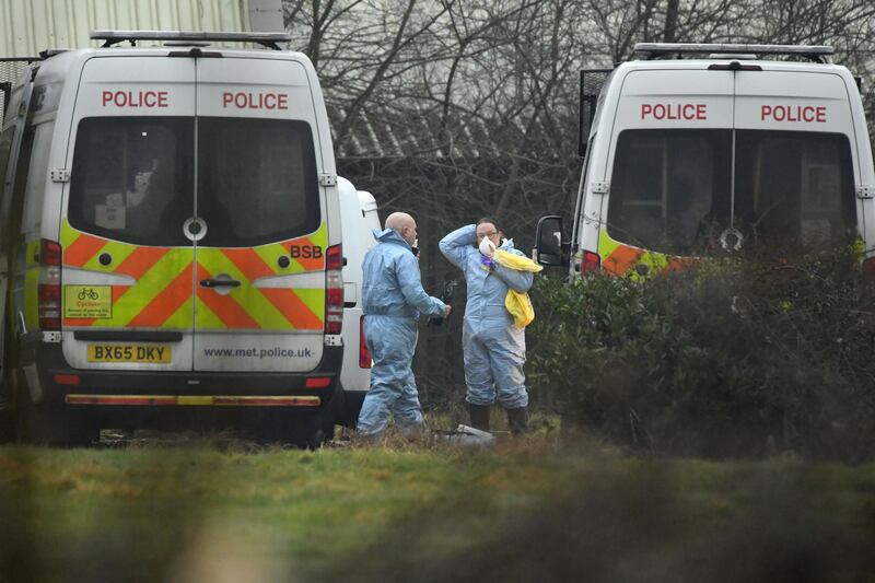 Police adjust their protective clothing beside police vans at a disused paintball centre on Bears Lane in Ashford. Getty Images