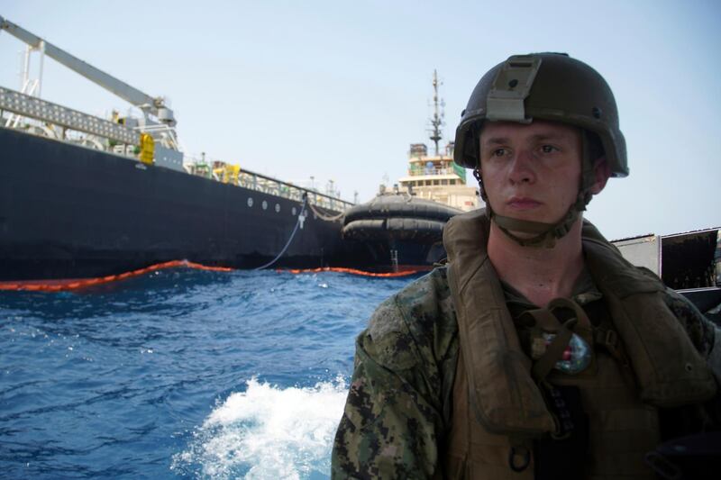The damaged Panama-flagged, Japanese owned oil tanker Kokuka Courageous is seen behind a US sailor, off Fujairah.  AP