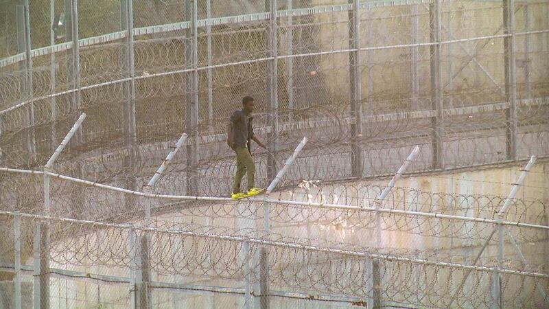 An African migrant in this still image from video climbs the border from Morocco to Spain's North African enclave of Ceuta, Spain, July 26, 2018.    FARO TV/REUTERS TV/via REUTERS  SPAIN OUT. NO COMMERCIAL OR EDITORIAL SALES IN SPAIN