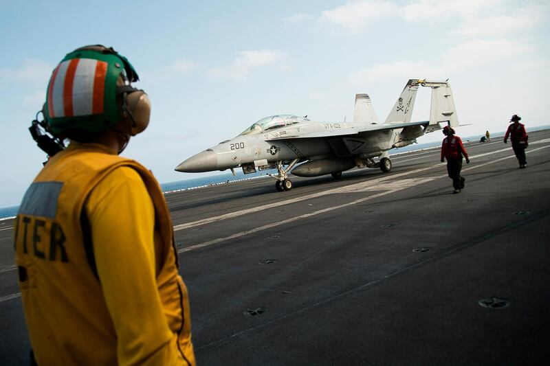 A crew member looks at a F/A-18 fighter jet on the deck of the USS Abraham Lincoln aircraft carrier in the Arabian Sea. AP