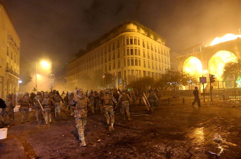 Smoke rises as Lebanese army soldiers walk during a protest against the newly formed government in Beirut. Reuters