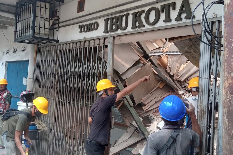 Workers inspect a store damaged during the earthquake. AP