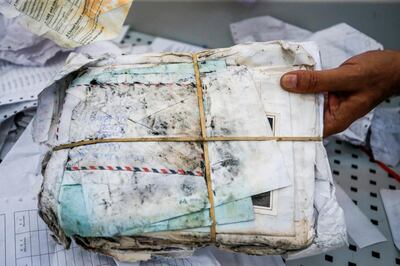 Ramadan Ghazawi, a Palestinian official at the central international exchange post office in the West Bank city of Jericho, holds up a stack of letters and postcards, among many items of previously undelivered mail dating as far back as 2010 which has been withheld by Israel, at the premises in Jericho on August 14, 2018. - Israel had held the post for years but handed it over to the Palestinian authorities after an agreement. (Photo by ABBAS MOMANI / AFP)