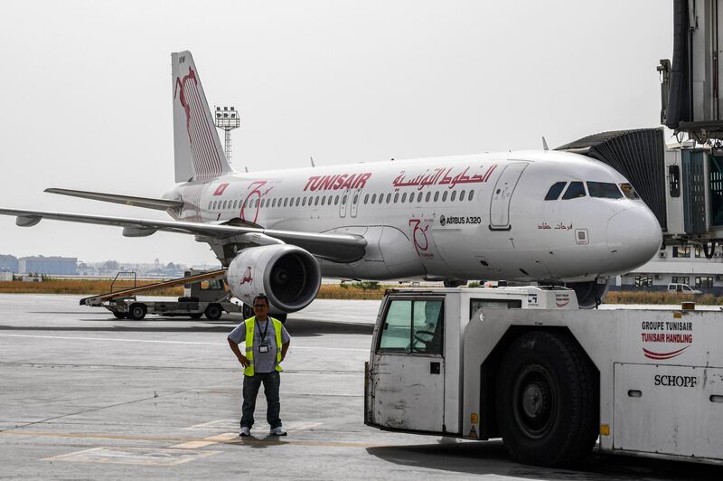 A worker of Tunis-Carthage International Airport stands near a TunisAir Airbus A320 aircraft on the tarmac at the airport in the Tunisian capital on June 27, 2020 as the North African country re-opens its land, sea, and air borders following a four-month closure due to the COVID-19 coronavirus pandemic. (Photo by FETHI BELAID / AFP)