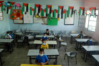 Palestinian students, wearing protective face masks, take their seats in their classroom on the first day of school in the village of Salem east of Nablus in the occupied West Bank on September 6, 2020, during the coronavirus pandemic. (Photo by JAAFAR ASHTIYEH / AFP)