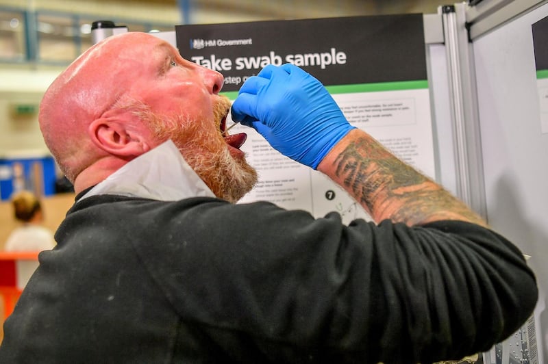 A testing staff member completes a lateral flow test swab, mandatory before opening to the public, at Rhydycar leisure centre in Merthyr Tydfil, Wales. AP Photo