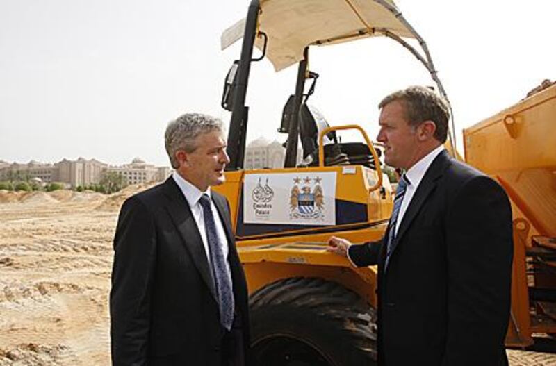 Manchester City manager Mark Hughes, left, with the club's chief executive Garry Cook at the new football pitch and City's official training headquarters in Abu Dhabi yesterday.