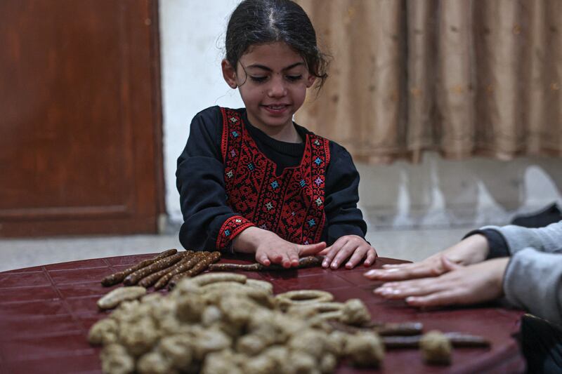 A Palestinian girl prepares traditional date-filled cookies with her family in Rafah, in the southern Gaza Strip. AFP