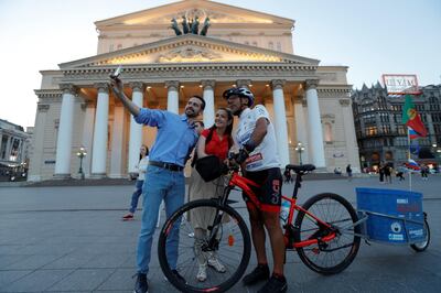 Portuguese cyclist Helder Batista, who arrived in Russia's capital to attend the 2018 FIFA World Cup, poses for a selfie with pedestrians in front of the Bolshoi Theatre in central Moscow, Russia June 18, 2018. REUTERS/Tatyana Makeyeva