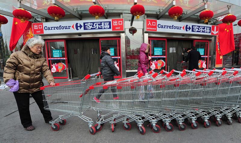 (FILES) In this file photo taken on January 27, 2011 A woman grabs a shopping cart outside a Carrefour store in Beijing. The French retailer Carrefour announced on June 23, 2019 that it will sell 80% of its activities in China to the Chinese group Suning.com for a total of 620 million euros. / AFP / Frederic J. BROWN
