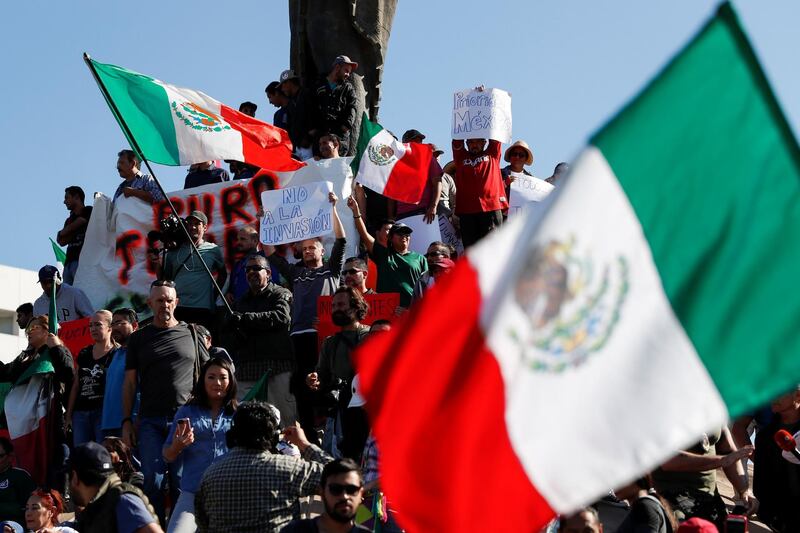 Demonstrators holding a placard that read, "Not to the invasion" and waving Mexican flags, attend a protest against migrants who are part of a caravan traveling en route to the United States, in Tijuana, Mexico November 18, 2018. REUTERS/Carlos Garcia Rawlins