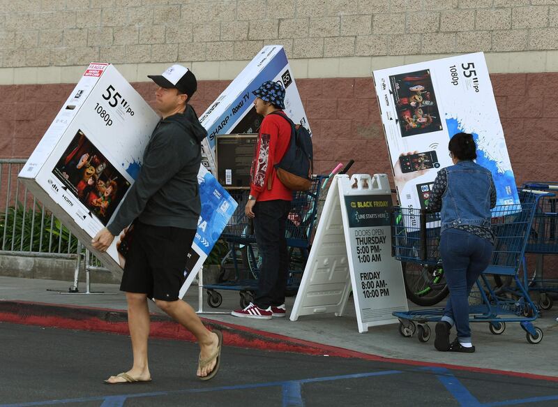 (FILES) This file photo taken on November 25, 2016 shows shoppers with their arms full walking to their cars during the "Black Friday" sales at a Best Buy store in Culver City. / AFP PHOTO / Mark RALSTON