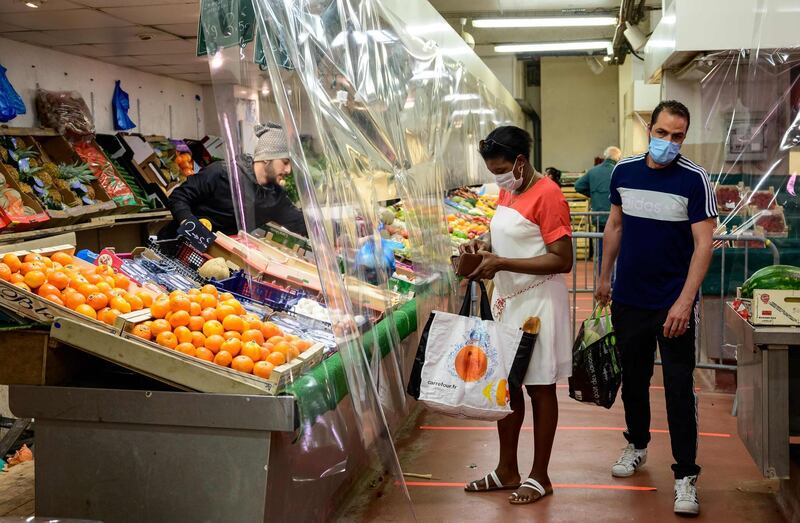 People wearing protective facemasks fot their grocery shopping next to fruits and vegetables stalls at a covered market in Le Perreux-sur-Marne.  AFP