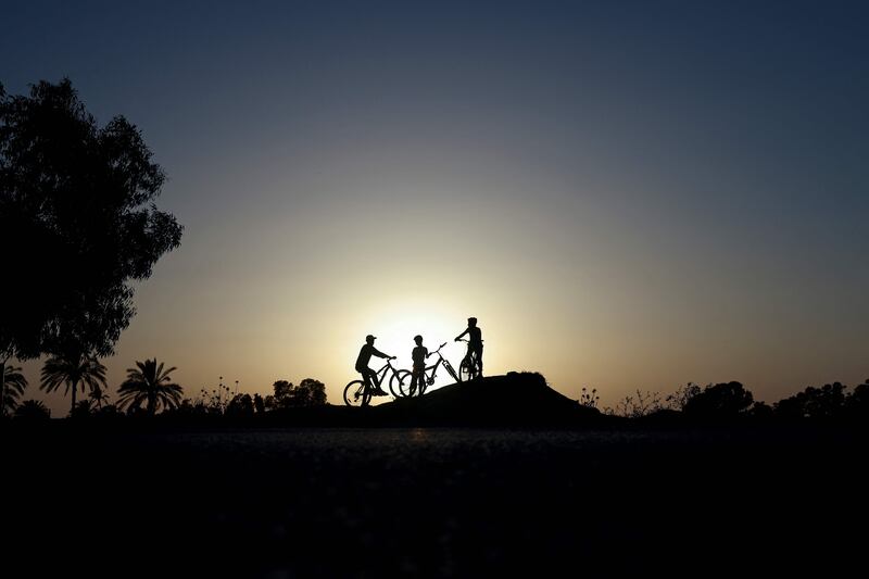 Palestinian children riding their bicycles during sunset in Gaza City. AFP