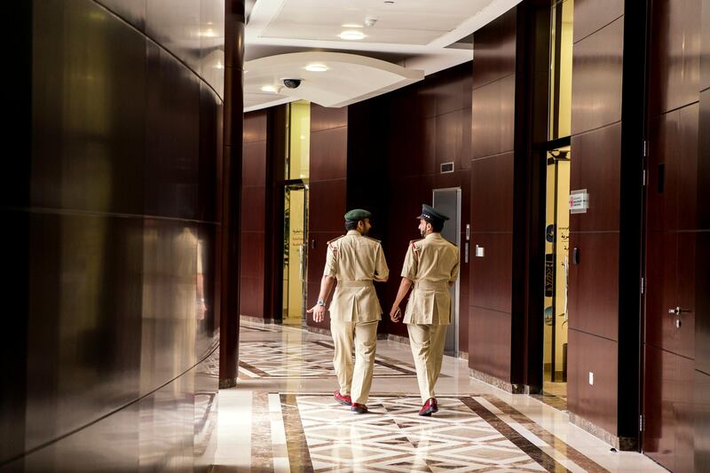 Two police officers walk down a corridor.