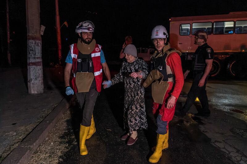 Red Cross volunteers help an elderly woman rescued from a flooded area in Kherson, Ukraine. Reuters