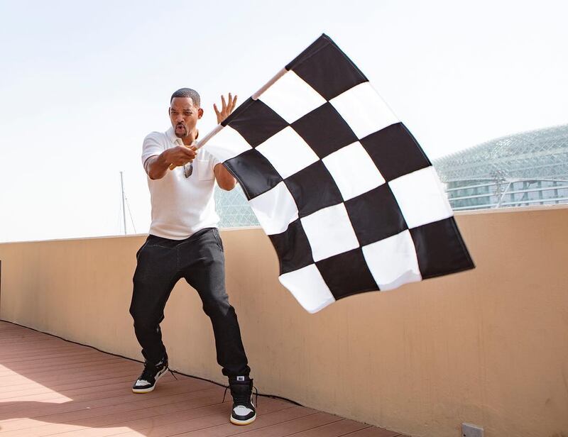 Will Smith waves a flag at the Abu Dhabi Grand Prix in 2018.