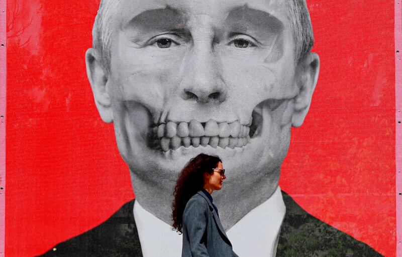 A Romanian woman passes by an image of Russian President Vladimir Putin, part of an anti-war art exhibition, in King's Square, near the Russian Federation's embassy compound, in Bucharest, Romania. EPA