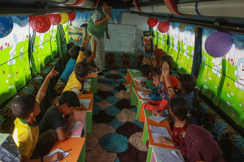 Displaced Syrian children take lessons on a bus converted into a classroom.
