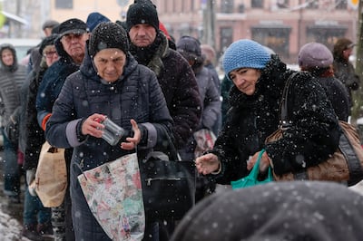 Elderly people receive food and gloves from a charity organisation in a snow-covered street in Kyiv, Ukraine. Getty Images