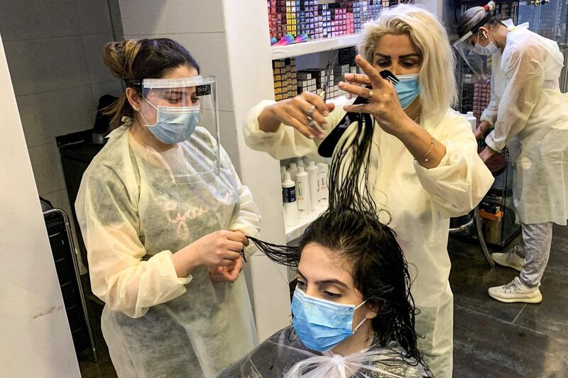 A hairdresser clad in face shield and mask cuts a client's hair at a women's salon in Saudi Arabia's capital Riyadh.   AFP
